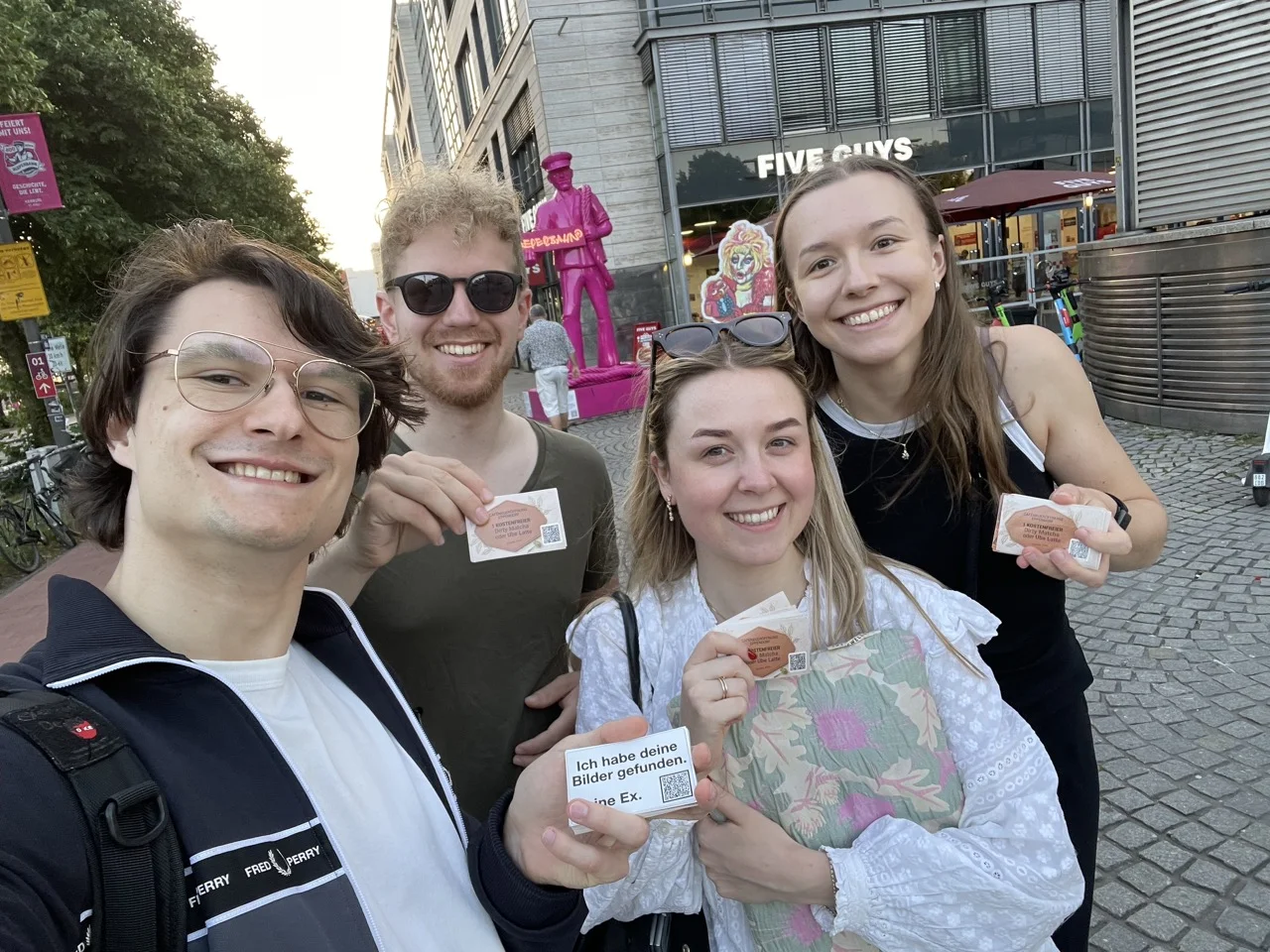 Four people on a Hamburg street holding Seeqr stickers up to the camera.